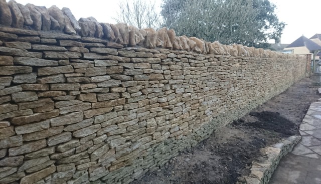 Dry stone wall height increase. Original wall height shown my green weathered stones near the base